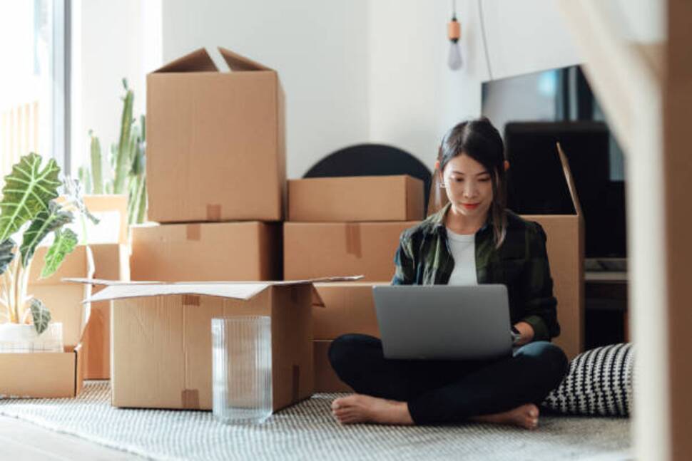 https-media-gettyimages-com-id-1425625153-photo-young-woman-using-laptop-while-sitting-on-the-floor-in-new-home-with-cardboard-boxes